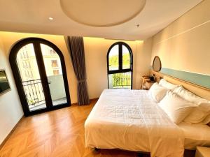a bedroom with a large bed and two windows at The Sol Hotel in Phú Quốc