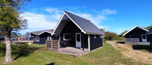 a black and white house with a porch at Tornby Strand Camping Cottages in Hirtshals