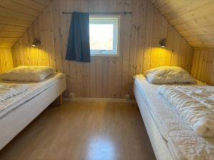 two beds in a room with a window at Tornby Strand Camping Cottages in Hirtshals +38 photos