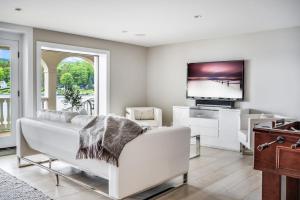 a living room with a white couch and a flat screen tv at Waterfront Lakehouse in New Fairfield