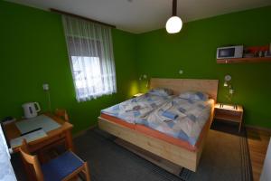a green bedroom with a bed and a desk at Guest House Žnidar in Bohinj