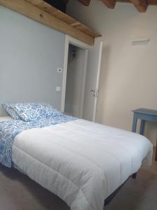 a bedroom with a white bed with a blue pillow and a table at Casina Borgo Castello in Civitella di Romagna