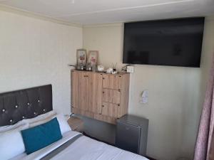 a bedroom with a bed and a flat screen tv at 25 Jacaranda Lodge & Backpackers in Pinetown