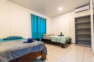 a bedroom with two beds and a blue curtain at Cahuita Apartment by Angie in Cahuita
