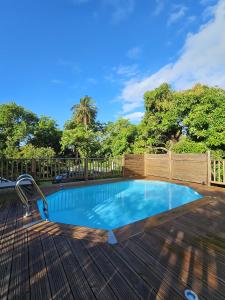 a pool on a deck with a fence and trees at Villa IXORA- piscine privée, vue montagne, calme absolu proche plages in Trois-Rivières