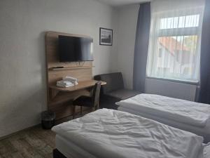 a hotel room with two beds and a desk with a tv at Voigt's Hofpension GbR in Zahna-Elster