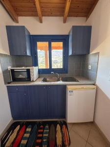 a kitchen with blue cabinets and a sink and a microwave at LifeHouse in Agia Pelagia