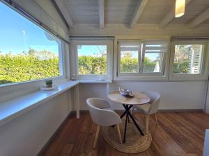 a small table and two chairs in a room with windows at Villa Lucy Eco Friendly in Fontane Bianche