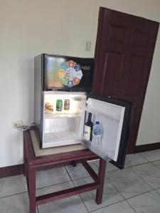 an open refrigerator sitting on top of a wooden table at Mandy's Villa in Bluefields