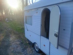 a white trailer with an open door in the woods at Yupfssi camp in Riga