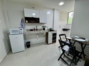 a small kitchen with a table and a white refrigerator at No centro, em frente à praça in Eunápolis