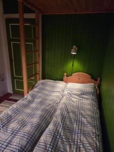 a bedroom with a bed with a green wall at Rorbu in Nusfjord, Lofoten in Nussfjord
