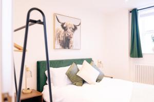 a bedroom with a bed with a cow picture on the wall at The Spa Town Loft in Buxton