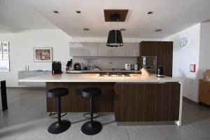 a kitchen with a island with bar stools in it at Hal Saghtrija - Gozo Hideaways in Żebbuġ