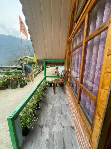 a porch of a building with a bench and windows at Golays homestay in Kalimpong