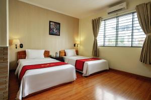 a room with two beds and a window at Khách Sạn Long Xuyên in Long Xuyên
