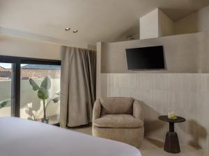 a bedroom with a chair and a tv on a wall at Blush - Crema - Leopard Apartments in Zakynthos