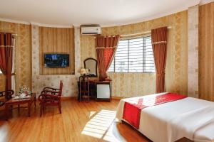 a bedroom with a bed and a table and a desk at Khách Sạn Long Xuyên in Long Xuyên