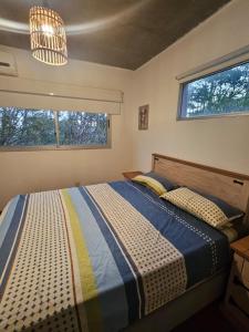 a bedroom with a bed and two windows at MarEz in Punta Del Diablo