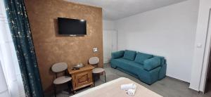 a living room with a blue couch and a tv at Vila Armonia in Curtea de Argeş