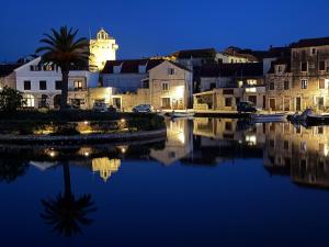 a city with a clock tower and a river at night at Apartmani Lada 2 in Vrboska