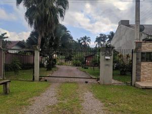 a gate in a yard with palm trees and a house at Condomínio Containers está localizado a 900m do centro de Morretes, local calmo e em meio a mata Atlântica in Morretes