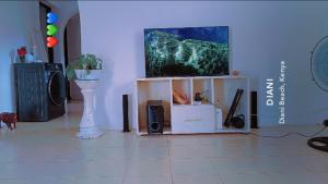 a living room with a flat screen tv on a tv stand at Honeymoon villah in Diani Beach