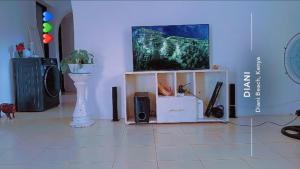 a living room with a flat screen tv on a tv stand at Honeymoon villah in Diani Beach