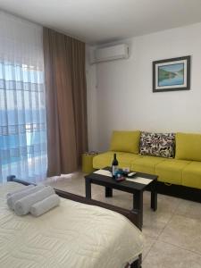 a living room with a yellow couch and a table at Apartmani Vila Delfin in Dobra Voda +58 photos