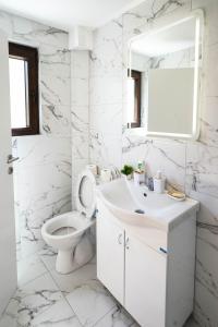 a white bathroom with a toilet and a sink at Josahouse in Bjeluša +14 photos