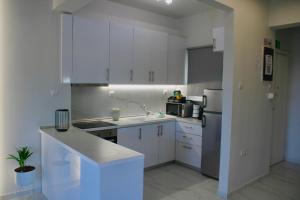 a kitchen with white cabinets and a sink and a refrigerator at Riviera Penthouse in Paleo Tsifliki