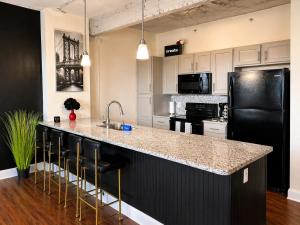 eine Küche mit einem schwarzen Kühlschrank und einer Theke mit Hockern in der Unterkunft EMLuxe in Memphis