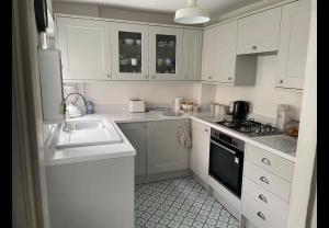 Eine Küche mit weißen Schränken, Spüle und Herd in der Unterkunft Faversham cottage in Kent