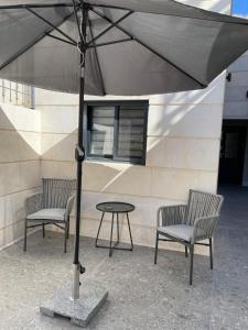 two chairs and a table under an umbrella at Malka Suites in Beit Shemesh