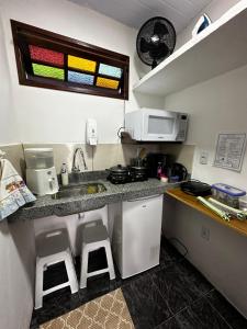 a kitchen with a sink and a microwave and stools at Recanto Divô e Divó in Ouro Preto