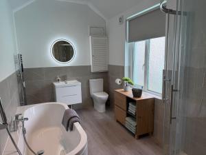 a bathroom with a tub and a toilet and a sink at Cockle Cottage in The Mumbles +29 photos