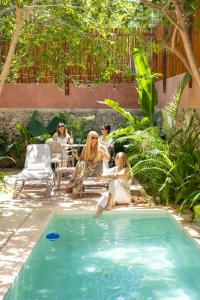 two women are sitting next to a swimming pool at Casa Sofía Centro in Mérida