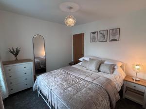 a bedroom with a bed and a dresser and a mirror at Cockle Cottage in The Mumbles