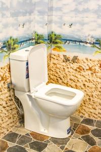 a toilet in a bathroom with a painting of a beach at Bees Honey Cottage Ella in Ella +54 photos
