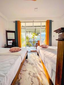 two beds in a room with a large window at Bees Honey Cottage Ella in Ella