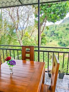 a wooden table with a vase of flowers on a balcony at Bees Honey Cottage Ella in Ella