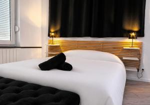 a bedroom with a white bed with a black pillow at Spacieux spa et sauna in Bourges