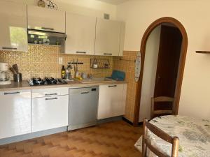 a kitchen with white cabinets and a sink and a table at Le petit gîte in Saint-Étienne-le-Laus