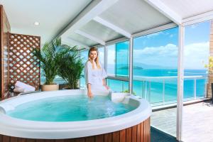 a woman sitting in a hot tub in a room with windows at Palace Praia Hotel in Florianópolis