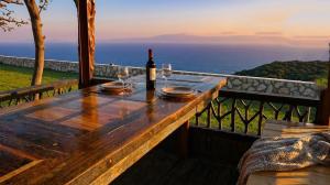 a wooden table with a bottle of wine and glasses at Panoramic Sea View Wooden Cottage Ratzakli, Kefalonia in Ratzaklíon