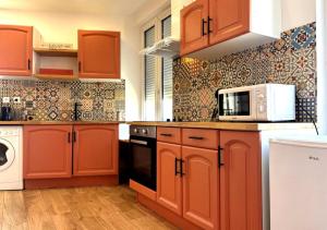 a kitchen with orange cabinets and a microwave at Spacieux spa et sauna in Bourges