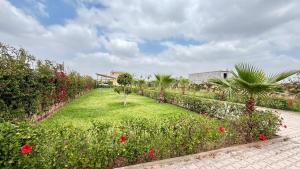 a garden with red flowers and trees and a building at villa Tarik with private pool in El Aïn