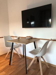 a table with two chairs and a television on a wall at Modernes Appartement - ruhig, zentrumsnah, abendsonnige Loggia in Bad Füssing