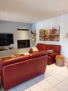 a living room with a red leather couch and a tv at Plaisirs de Lège in Lège-Cap-Ferret