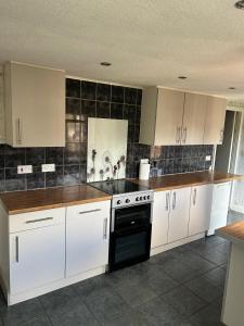 a kitchen with white cabinets and a black oven at Rehoboth place in Nottingham